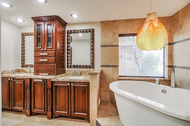 bathroom with tile patterned floors, vanity, a bathtub, and tile walls