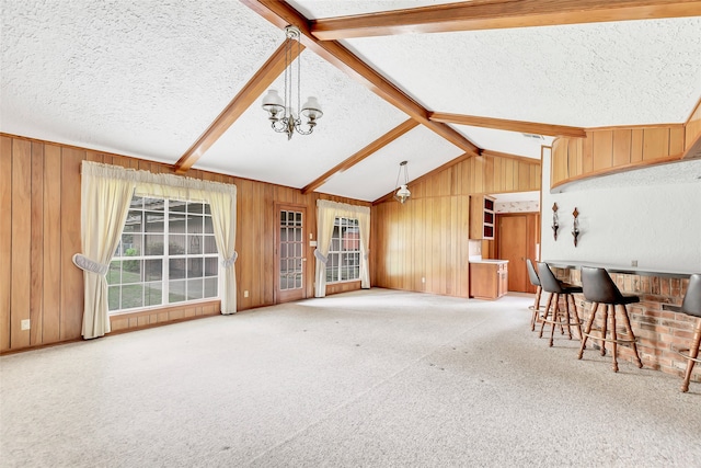 unfurnished living room with carpet flooring, lofted ceiling with beams, a textured ceiling, and a notable chandelier