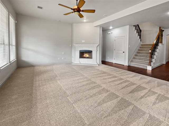 unfurnished living room featuring ceiling fan and dark carpet