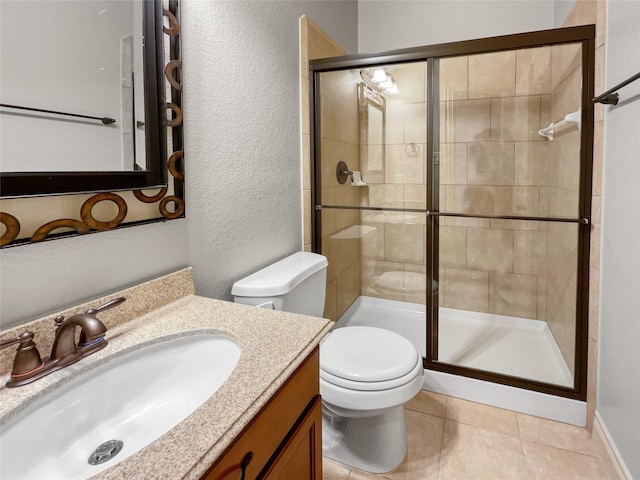 bathroom featuring toilet, large vanity, a shower with shower door, and tile flooring