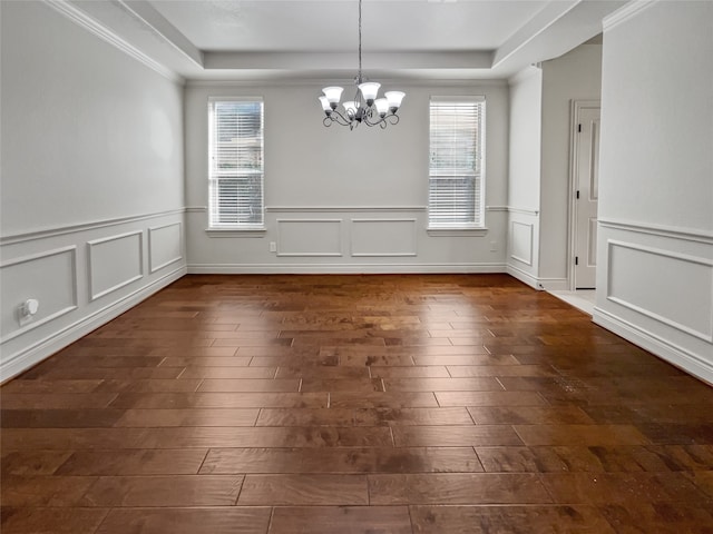 spare room featuring dark hardwood / wood-style flooring, a raised ceiling, ornamental molding, and a chandelier