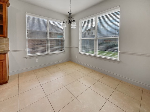 unfurnished dining area featuring a chandelier and light tile floors