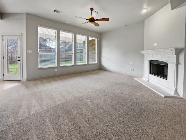 unfurnished living room with ceiling fan, light colored carpet, and plenty of natural light