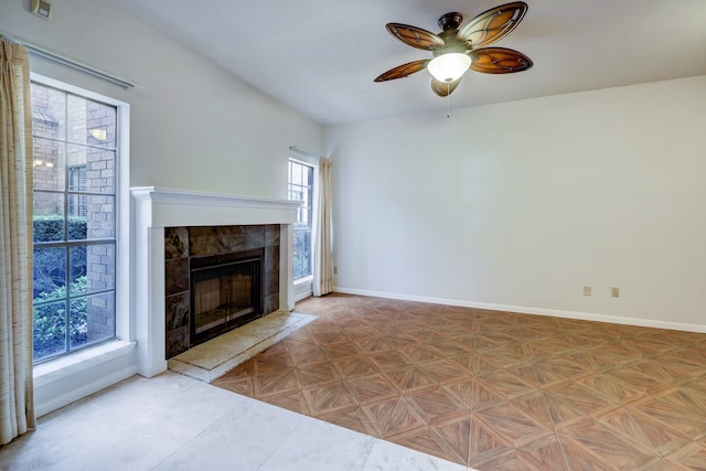 unfurnished living room featuring ceiling fan, light parquet floors, a tile fireplace, and plenty of natural light