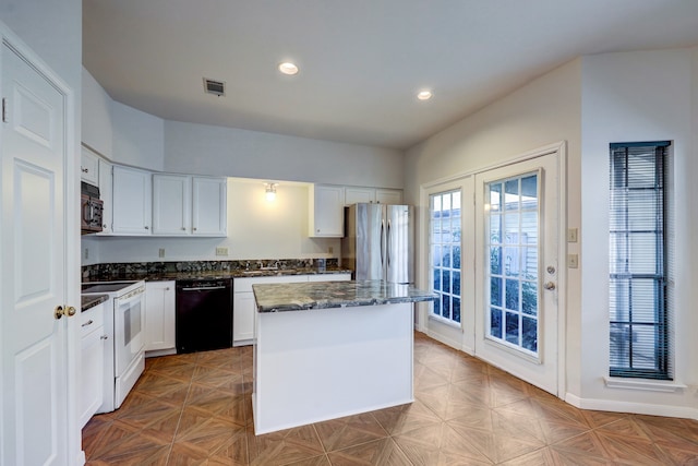 kitchen with appliances with stainless steel finishes, light parquet floors, a kitchen island, and white cabinets