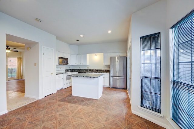 kitchen featuring white cabinets, white range with electric stovetop, a kitchen island, light parquet floors, and stainless steel refrigerator