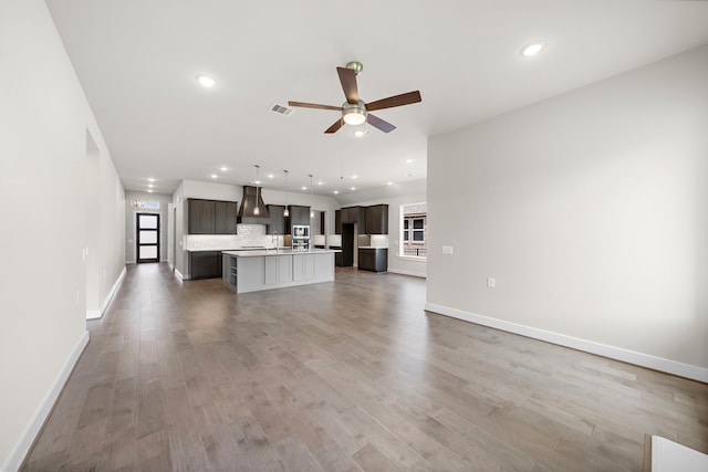 unfurnished living room with ceiling fan and hardwood / wood-style floors