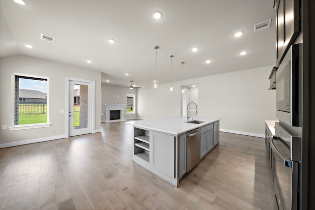 kitchen featuring gray cabinets, a kitchen island with sink, sink, and light hardwood / wood-style flooring