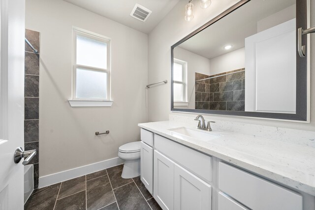 bathroom featuring a tile shower, tile patterned flooring, vanity, and toilet