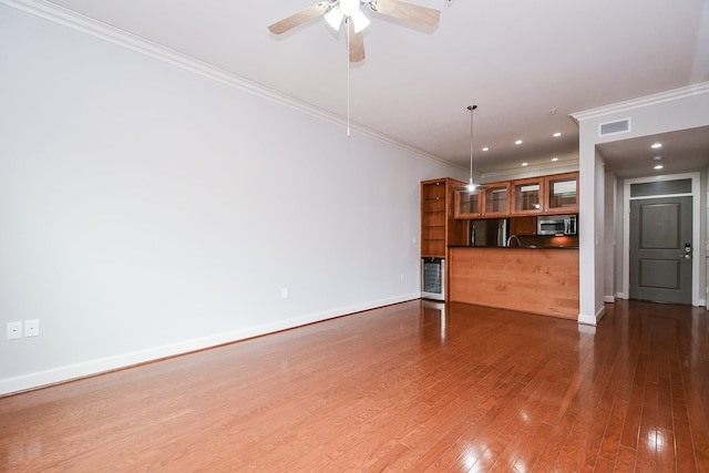 unfurnished living room featuring crown molding, ceiling fan, hardwood / wood-style flooring, and wine cooler