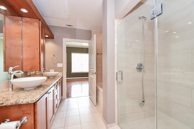 bathroom featuring a shower with shower door, dual sinks, tile floors, and vanity with extensive cabinet space