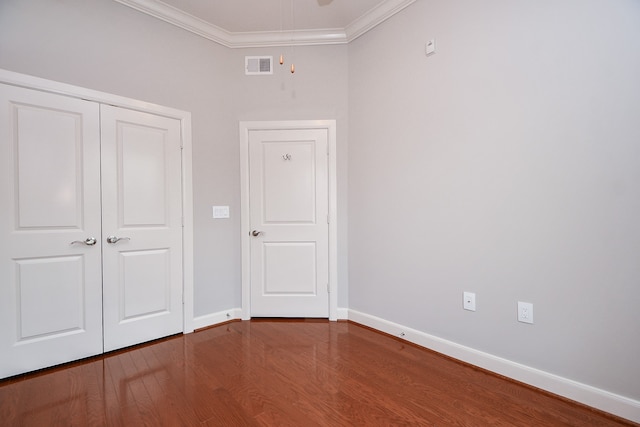 unfurnished bedroom featuring crown molding, dark hardwood / wood-style floors, and a closet