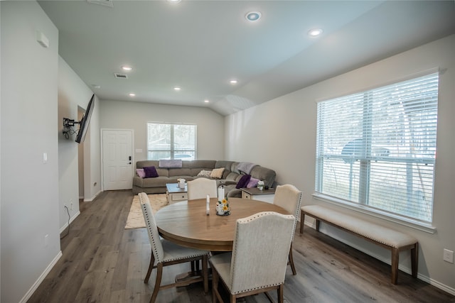 dining space with wood-type flooring and vaulted ceiling