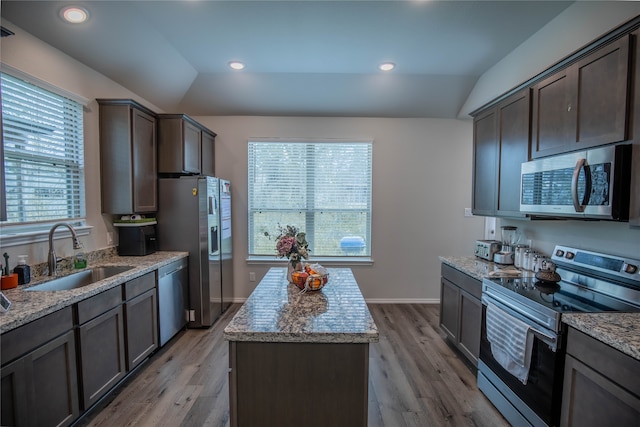 kitchen with light stone counters, light hardwood / wood-style floors, sink, lofted ceiling, and stainless steel appliances