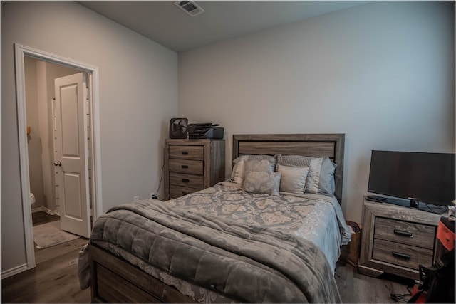 bedroom featuring ensuite bath and dark wood-type flooring