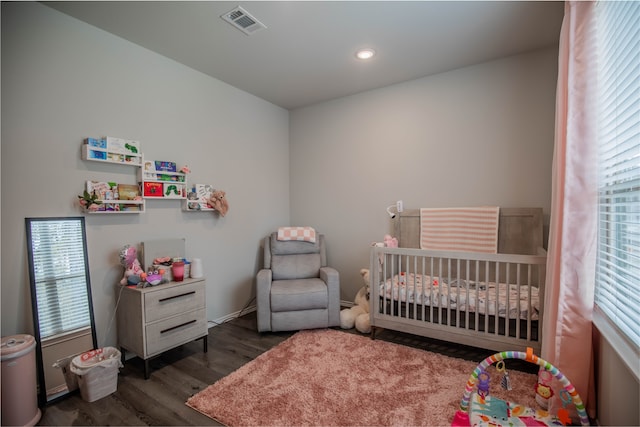 bedroom featuring a crib and dark wood-type flooring