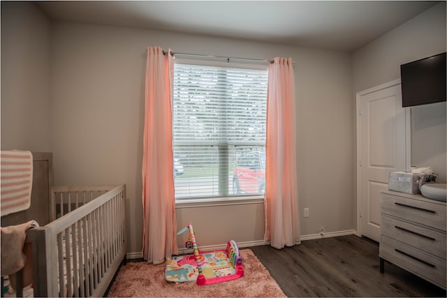 bedroom featuring a crib and dark hardwood / wood-style flooring