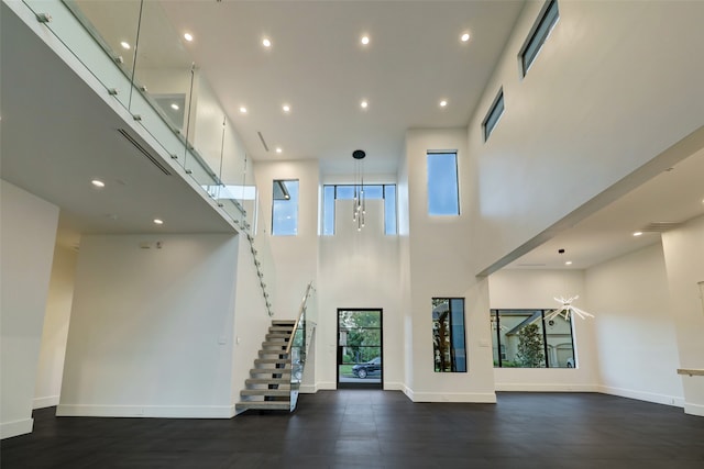 unfurnished living room featuring an inviting chandelier, dark hardwood / wood-style flooring, and a high ceiling