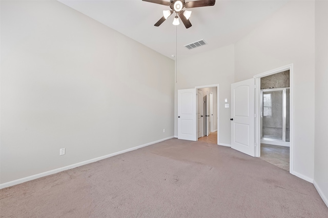 unfurnished bedroom with ceiling fan, connected bathroom, light colored carpet, and high vaulted ceiling