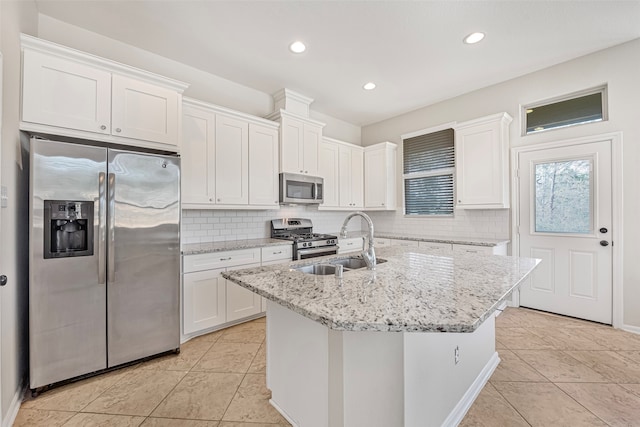 kitchen featuring an island with sink, tasteful backsplash, appliances with stainless steel finishes, white cabinetry, and sink