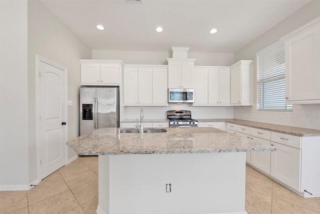 kitchen with appliances with stainless steel finishes, a kitchen island with sink, sink, and tasteful backsplash