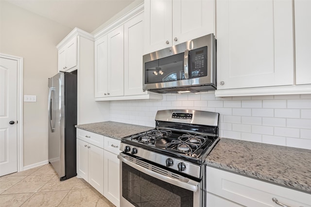 kitchen featuring light tile floors, light stone counters, backsplash, stainless steel appliances, and white cabinetry