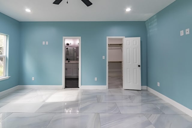 unfurnished bedroom with ceiling fan, a closet, a walk in closet, and ensuite bath