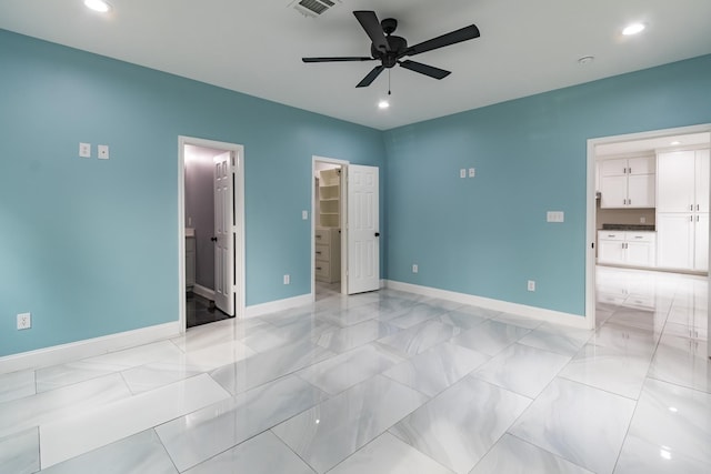 unfurnished bedroom featuring ensuite bath, a spacious closet, a closet, and ceiling fan