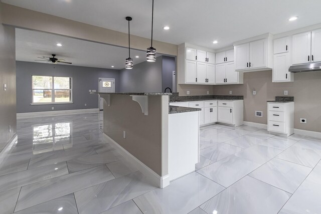 kitchen featuring dark stone counters, ceiling fan, sink, white cabinets, and hanging light fixtures