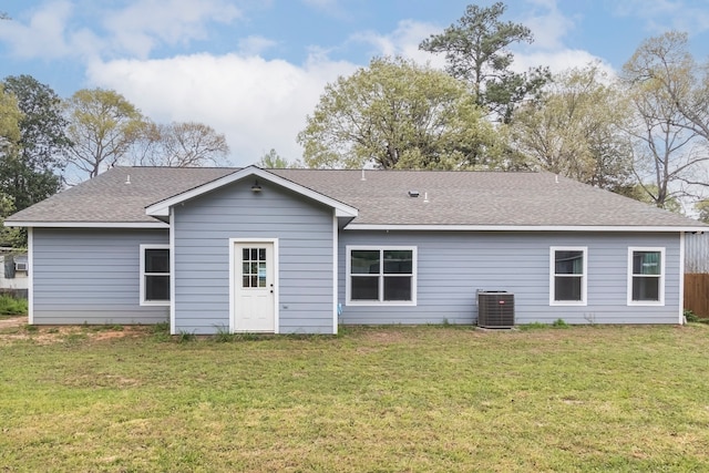 rear view of property featuring a lawn and central air condition unit