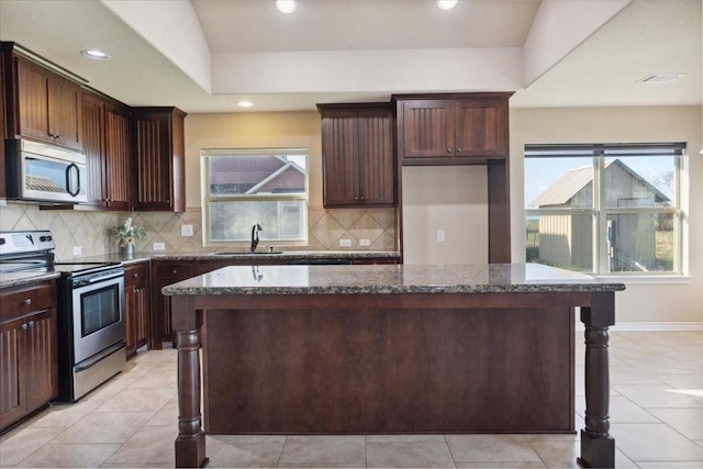 kitchen with dark stone countertops, a center island, and appliances with stainless steel finishes