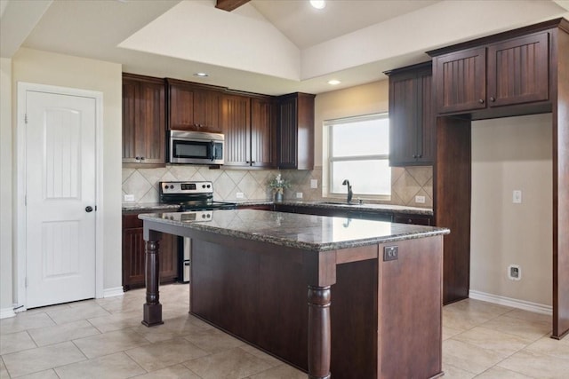 kitchen with a kitchen island, lofted ceiling, appliances with stainless steel finishes, and dark stone counters