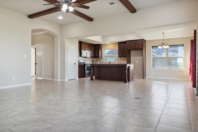 kitchen featuring appliances with stainless steel finishes, light tile patterned floors, pendant lighting, and beam ceiling