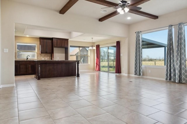 kitchen with beam ceiling, dark brown cabinetry, sink, decorative light fixtures, and light tile patterned floors