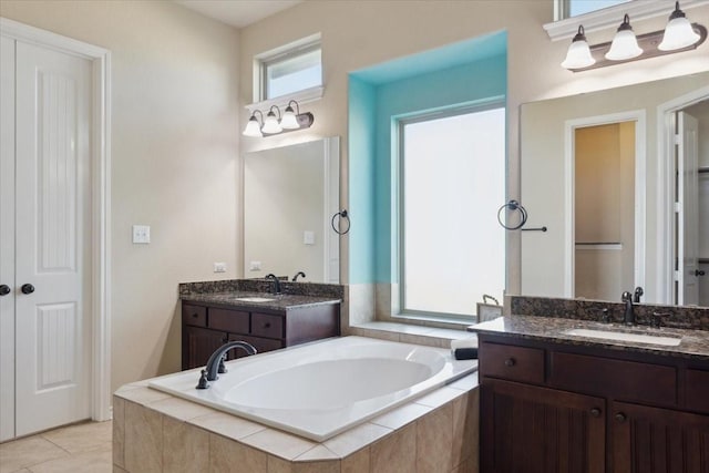 bathroom with tile patterned flooring, vanity, and a relaxing tiled tub