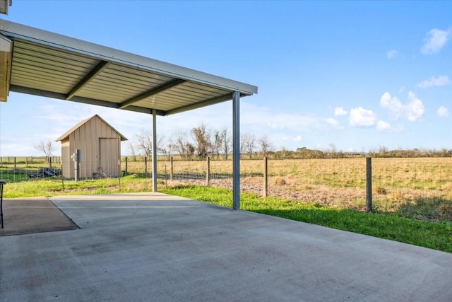 view of patio / terrace featuring a rural view and a shed