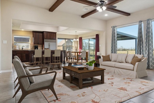 living room featuring beam ceiling, ceiling fan with notable chandelier, and sink