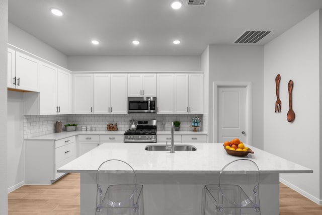 kitchen with white cabinetry, a kitchen island with sink, sink, and stainless steel appliances