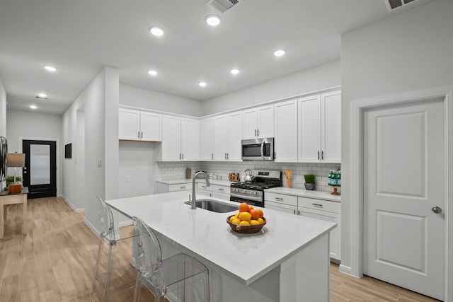 kitchen with sink, white cabinetry, stainless steel appliances, and a kitchen island with sink