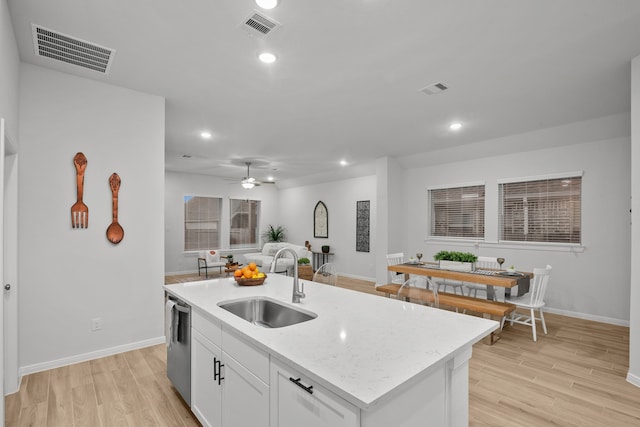 kitchen featuring white cabinets, light hardwood / wood-style floors, sink, and a kitchen island with sink