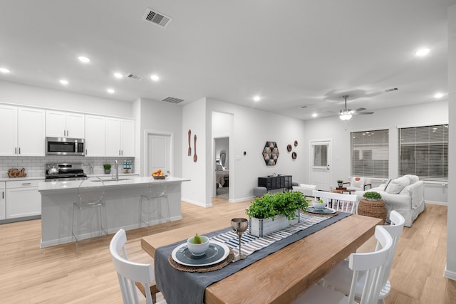 dining room with ceiling fan, light hardwood / wood-style floors, and sink