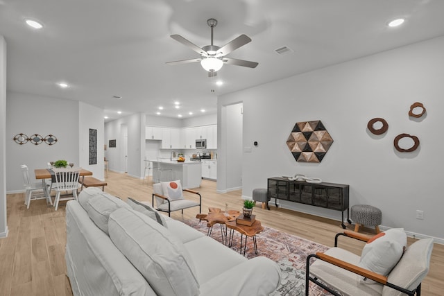 living room featuring ceiling fan and light hardwood / wood-style flooring