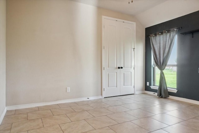 empty room featuring light tile patterned floors and vaulted ceiling