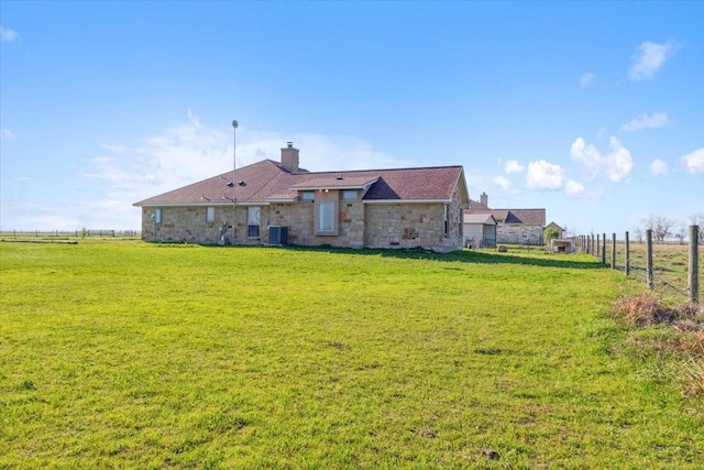 rear view of property featuring a lawn and a rural view