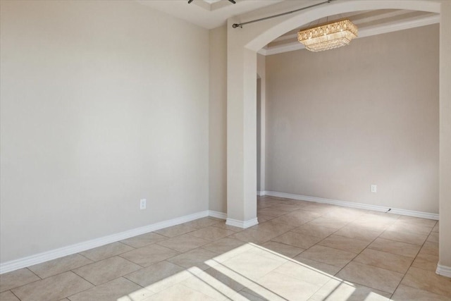 spare room featuring light tile patterned floors, crown molding, and a notable chandelier