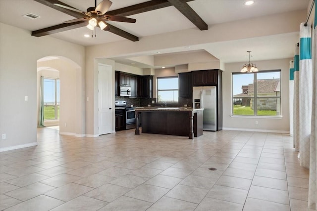 kitchen with beamed ceiling, decorative backsplash, dark brown cabinets, a kitchen island, and appliances with stainless steel finishes