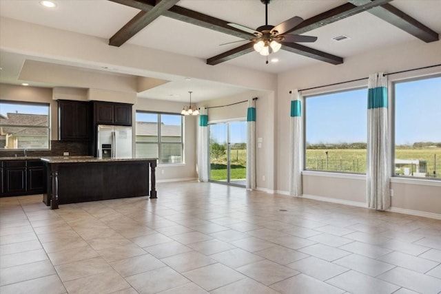 kitchen featuring light stone countertops, a kitchen island, stainless steel refrigerator with ice dispenser, light tile patterned floors, and ceiling fan with notable chandelier