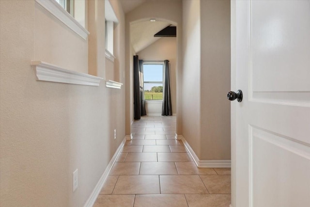 corridor featuring light tile patterned floors and lofted ceiling