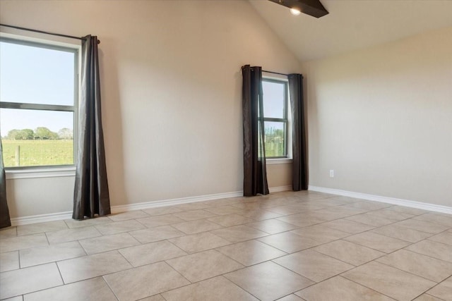 empty room featuring ceiling fan, light tile patterned floors, and vaulted ceiling