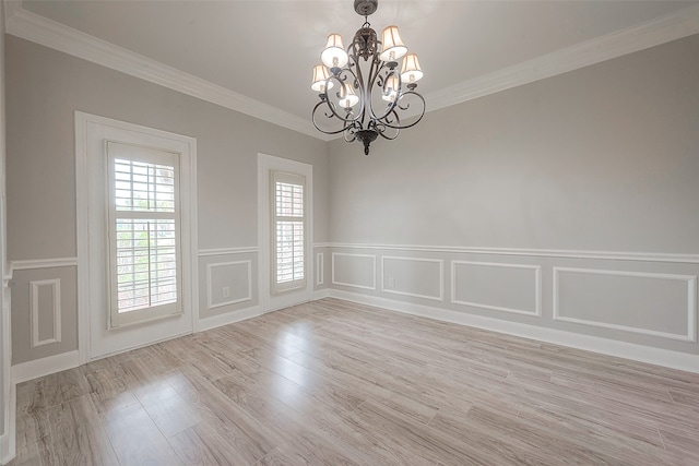 empty room featuring an inviting chandelier, ornamental molding, and light wood-type flooring